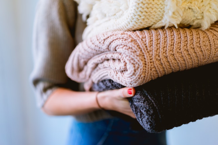 podzimní fotografické nápady pro instagram - dívka se složenými svetry v ruce